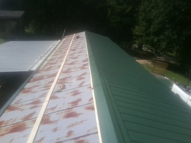 Old rusted panels beside newly installed green metal roofing — Wind Damage Roof Repair by Roofing Brothers in Quincy